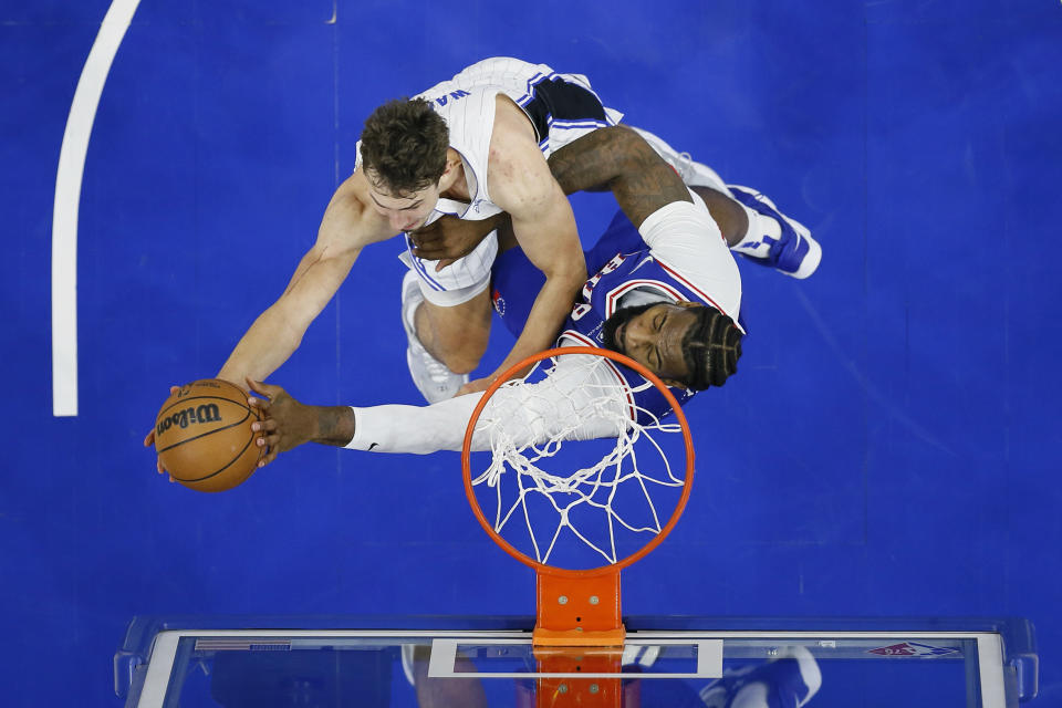 Orlando Magic's Franz Wagner, left, goes up for a shot against Philadelphia 76ers' Andre Drummond during the first half of an NBA basketball game, Monday, Nov. 29, 2021, in Philadelphia. (AP Photo/Matt Slocum)