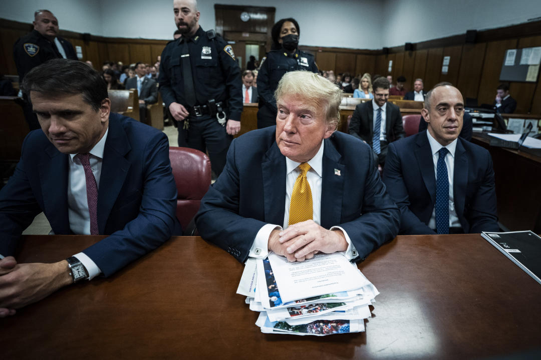 Former President Donald Trump sits in Manhattan criminal court with a stack of papers on the table in front of him..