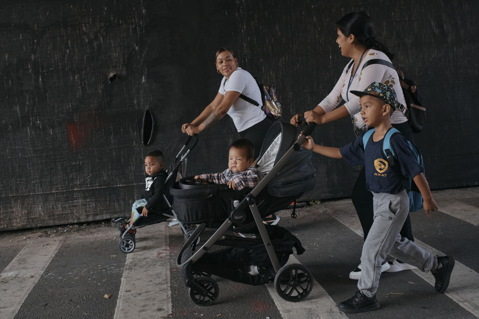 Kimberly Carchipulla, top right, and her 5 year old son Damien Salinas, bottom right, walk to school on Thursday, Sept. 7, 2023, in New York. Damien attends his first day of school in New York City after his family emigrated from Ecuador in June. Carchipulla and her family have been living in a room at the historic Roosevelt Hotel, converted into a city-run shelter for newly arrived migrant families hoping to find work, a new home and a better life for their children. (AP Photo/Andres Kudacki)