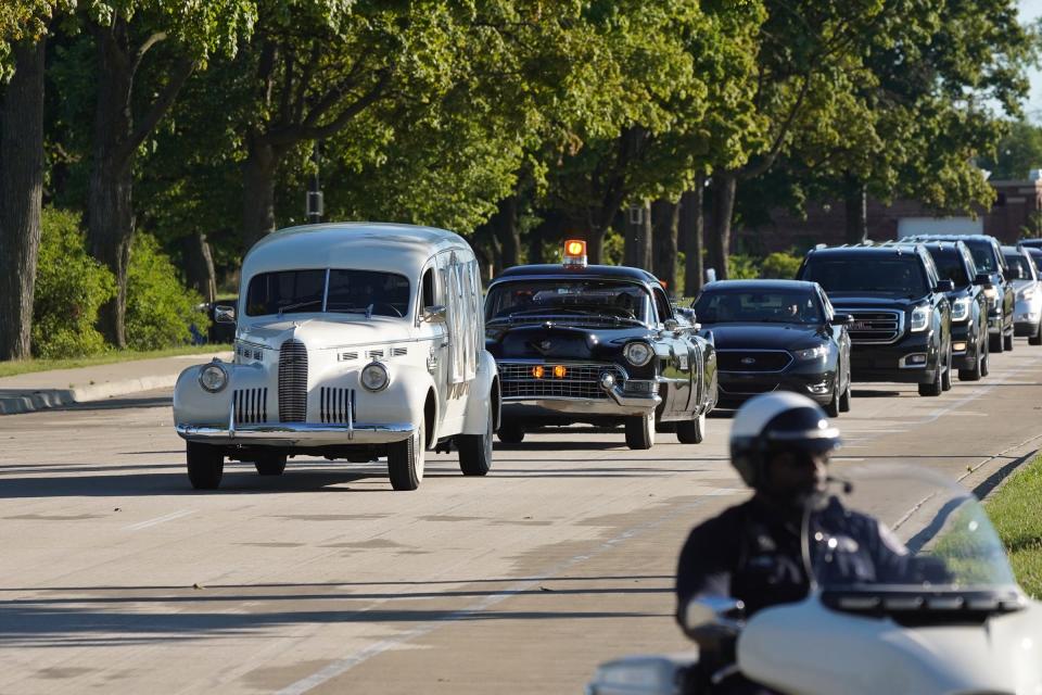 A hearse from Swanson Funeral leads a procession past photos of Detroit residents and people with connections to Detroit who died during the pandemic as part of the Memorial Drive on Belle Isle in Detroit on Monday, Aug. 31, 2020.