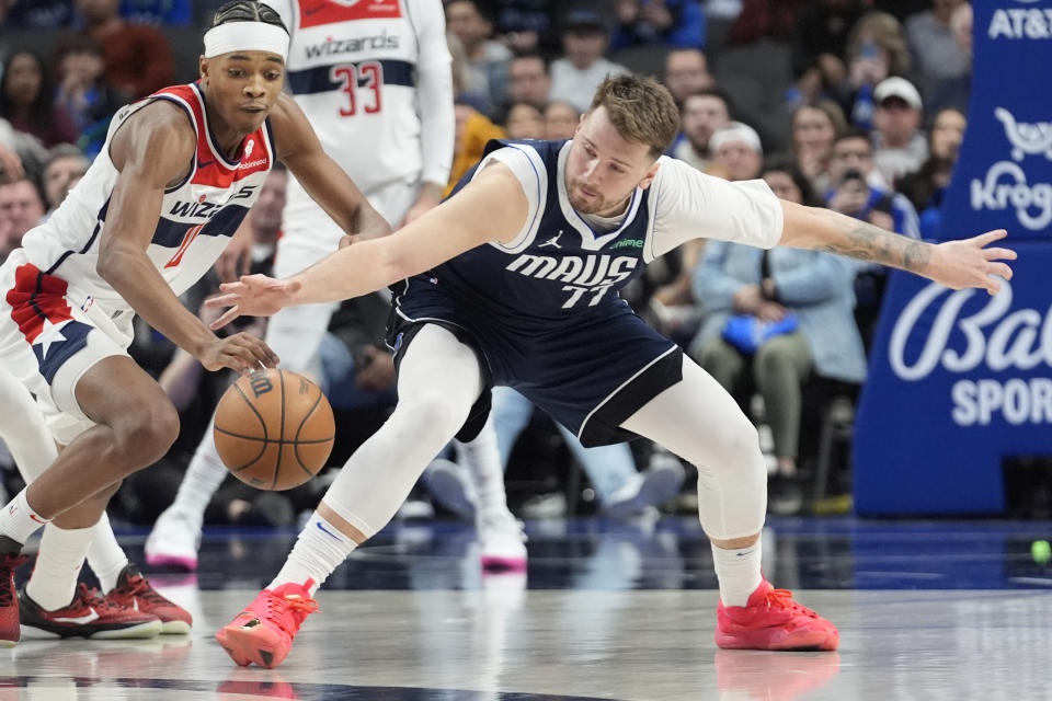 Dallas Mavericks guard Luka Doncic (77) reaches for the ball against Washington Wizards guard Bilal Coulibaly, left, during the second half of an NBA basketball game in Dallas, Monday, Feb. 12, 2024. (AP Photo/LM Otero)