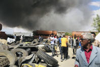 People are seen in front of clouds of black smoke from fires in the aftermath at the scene of an airstrike in Mekele, the capital of the Tigray region of northern Ethiopia Wednesday, Oct. 20, 2021. New airstrikes have hit Mekele, residents said Wednesday, as Ethiopia's government said it was targeting facilities to make and repair weapons, which a spokesman for the rival Tigray forces denied. (AP Photo)