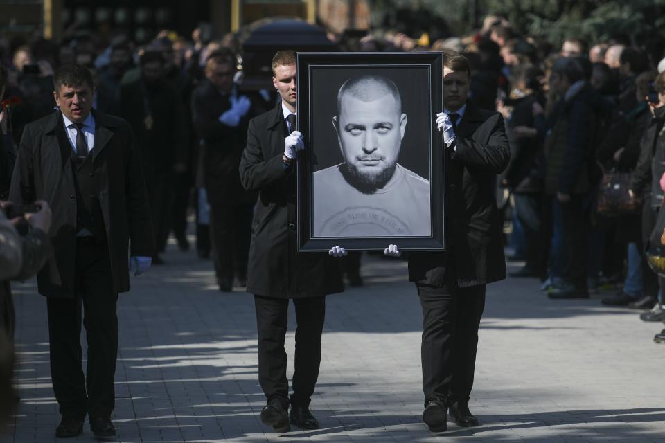 Cemetery workers carry a portrait of slain Russian military blogger Vladlen Tatarsky, during a funeral ceremony at the Troyekurovskoye cemetery in Moscow, Russia, Saturday, April 8, 2023. Tatarsky, known by his pen name of Maxim Fomin, was killed on Sunday, April 2, as he led a discussion at a riverside cafe in the historic heart of St. Petersburg, Russia's second-largest city. (Anton Velikzhanin, M24/Moscow News Agency via AP)