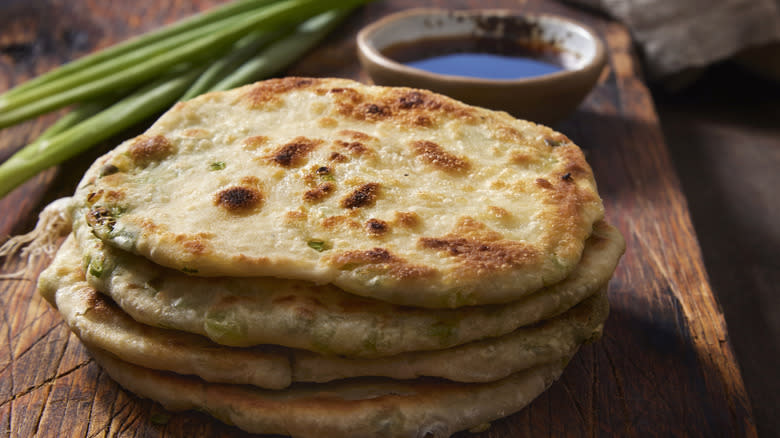 chinese scallion pancakes stacked with a soy dipping sauce