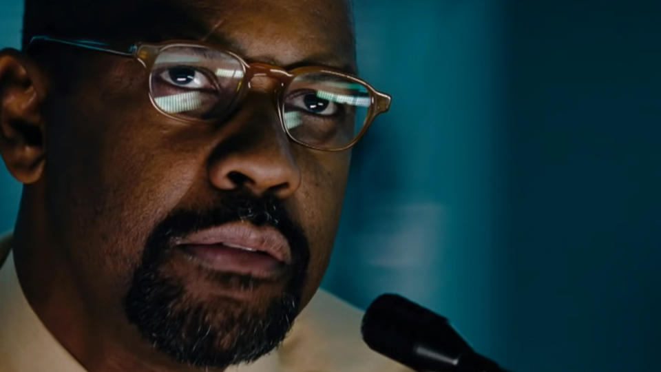 A close up of Denzel Washington wearing glasses and wearing a headset