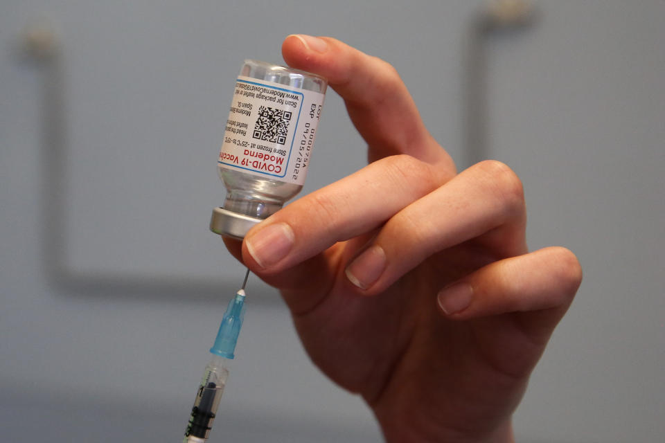 A syringe is inserted into a Moderna COVID-19 vaccine.