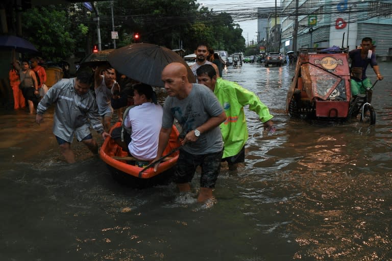 Residentes se abren paso por una calle inundada en Manila, la capital de Filipinas, el 24 de julio de 2024 (Ted ALJIBE)