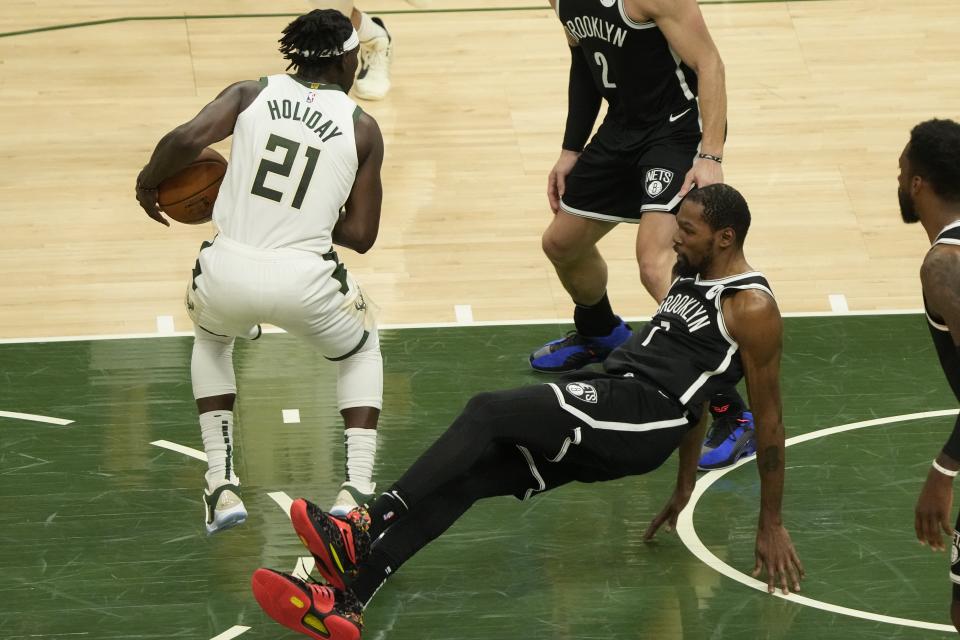 Milwaukee Bucks' Jrue Holiday is called for a charge on Brooklyn Nets' Kevin Durant during the first half of Game 4 of the NBA Eastern Conference basketball semifinals game Sunday, June 13, 2021, in Milwaukee. (AP Photo/Morry Gash)