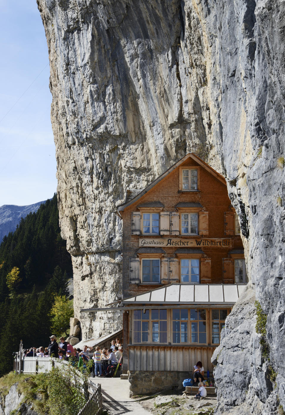 FILE - In this Oct. 14, 2014 file photo people take a break outside the Gasthaus Aescher near Ebenalp, Switzerland. The Gasthaus Aescher, built into a cliff above a valley in northeastern Switzerland, has been run by the same family since 1987. Authorities in Appenzell-Innerrhoden canton said Monday, Aug. 20, 2018 that the current tenants, Nicole and Bernhard Knechtle-Fritsche, are giving up the lease at the end of the 2018 season. (Steffen Schmidt/Keystone via AP)