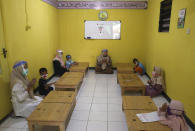 Teachers and students wearing protective gear as a precaution against the new coronavirus outbreak pray during a class at a Quran educational facility outside Jakarta, Indonesia, Wednesday, July 1, 2020. The government of Indonesia's capital region is extending the first transition phase from large-scale social restrictions in Jakarta as the number of new confirmed coronavirus cases continues to rise. (AP Photo/Tatan Syuflana)