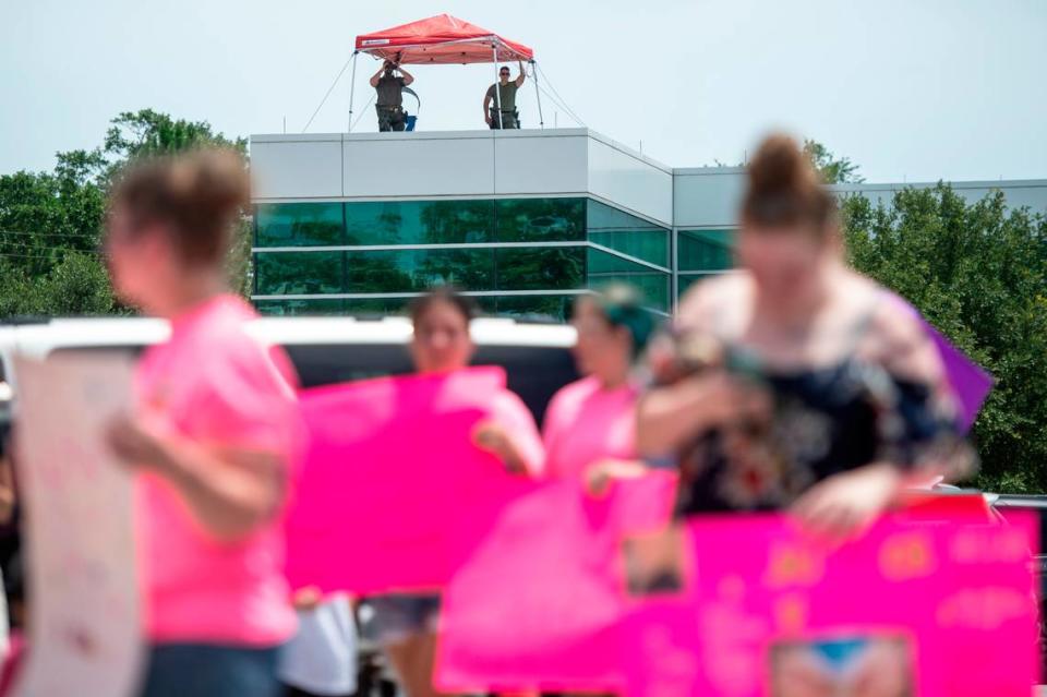 Members of law enforcement watch protestors from the roof of the Jackson County General Services building as a hearing in a chancery court case involving Heather Wyatt takes place in the adjacent courthouse on Thursday, July 18, 2024.