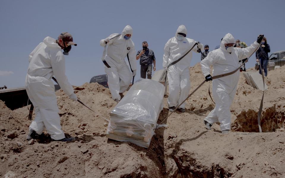 Gravediggers carry the casket of a person who died from the coronavirus at Municipal Cemetery No. 13 in Tijuana, Mexico - Bloomberg