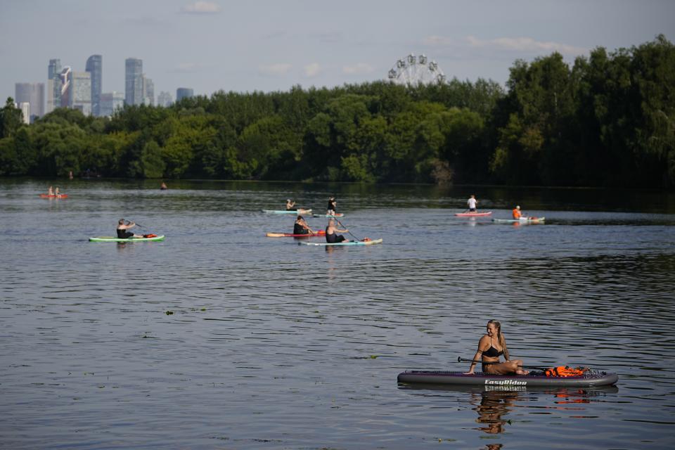 A woman sits on a SUP-board in Moskva river at Serebryany Bor park in Moscow, Russia, Thursday, July 11, 2024. Warm weather has settled in Moscow with a temperature of 30 Celsius, (86 Fahrenheit) and will increase in the coming days. (AP Photo/Pavel Bednyakov)