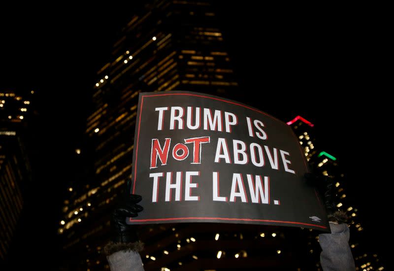 A protester lifts a sign into the air during a rally to support the impeachment and removal of President Trump in Seattle