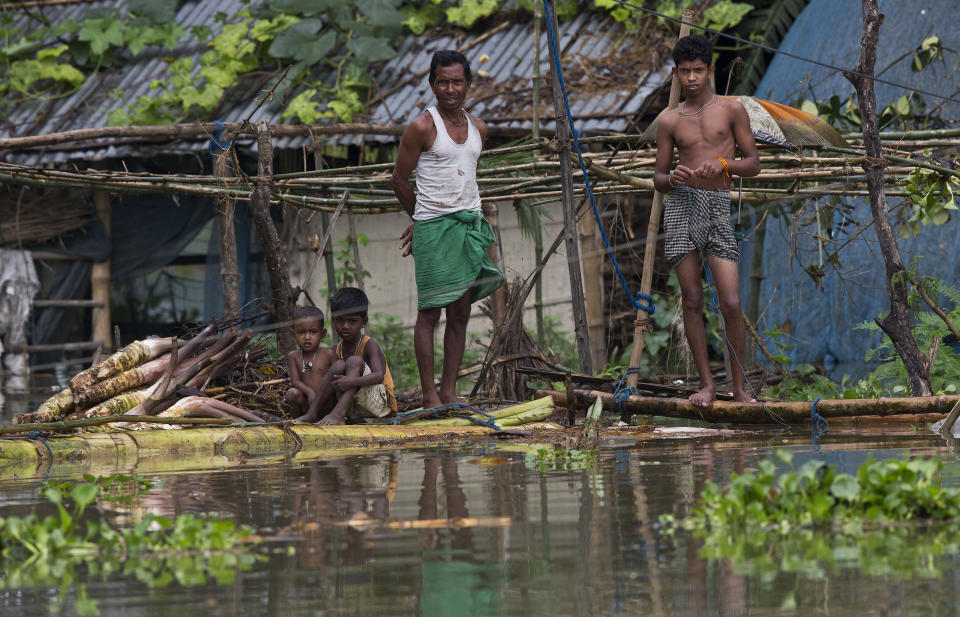 A flood affected family stands on a banana raft near their submerged house in Burgaon, east of Gauhati, Assam, India, Monday, July 15, 2019. After causing flooding and landslides in Nepal, three rivers are overflowing in northeastern India and submerging parts of the region, affecting the lives of more than 2 million, officials said Monday. (AP Photo/Anupam Nath)