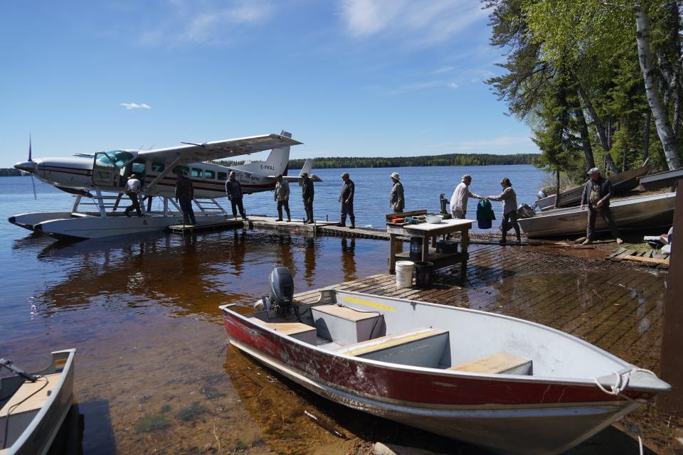 Guests to remote cabins on Seseganaga Lake near Ignace, Ontario, form a line to unload gear from a float plane.