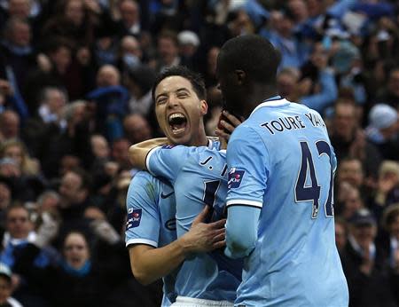 Manchester City's Jesus Navas (obscured) celebrates with team mates Yaya Toure (R) and Samir Nasri (L) after scoring goal against Sunderland during their English League Cup final soccer match at Wembley Stadium in London March 2, 2014. REUTERS/Suzanne Plunkett