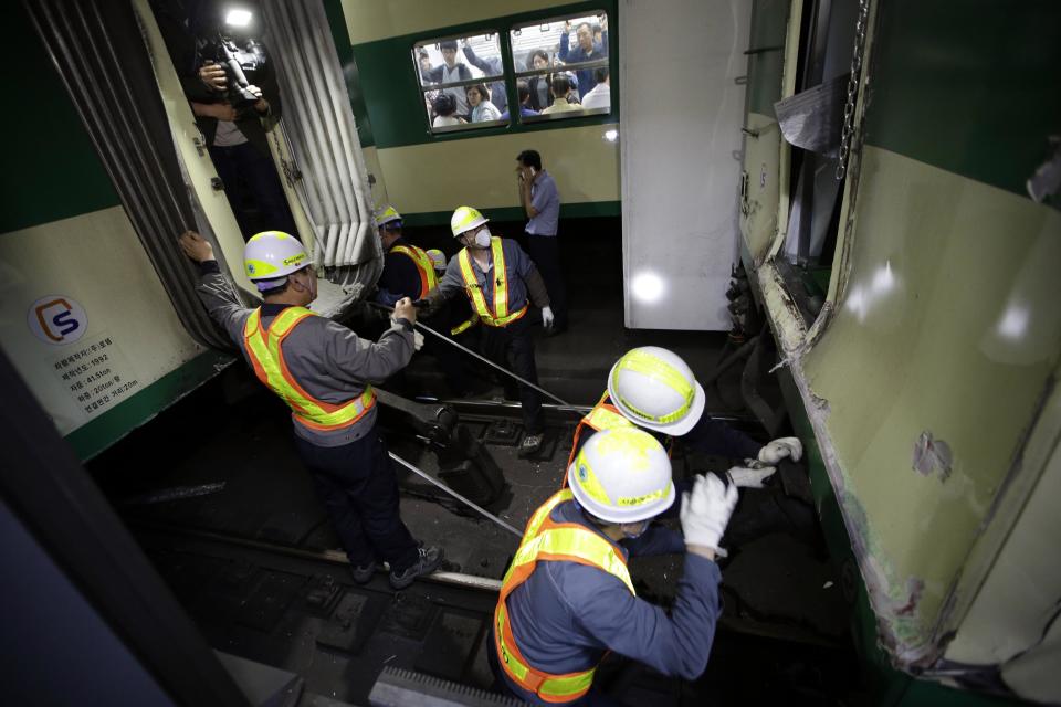 South Korea's subway workers try to repair a train after its collision at Sangwangshipri station in Seoul, South Korea, Friday, May 2, 2014. A subway train plowed into another train stopped at the station Friday, causing minor injuries for scores of people, a city official said. (AP Photo/Lee Jin-man)