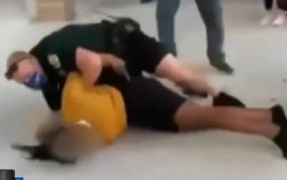 Screen grab from social media video shows school resource officer in Liberty High School in Kissimmee, Florida beginning to handcuff female student he'd slammed to the ground in a hallway. / Credit: WKMG-TV