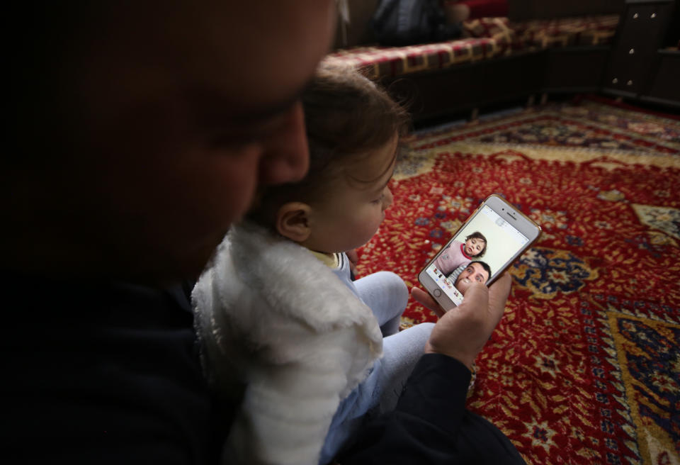 In this Sunday, Feb. 23, 2020 photo, Abdullah Mohammed plays with his daughter, three-year-old Salwa inside a house he recently fled to, near the Syrian-Turkish border, in Sarmada, Syria. Mohammed would do anything for his daughter, even if that means forcing himself to laugh with her at the sound of exploding bombs, to help her overcome her fear. Mohammed and Salwa became an overnight celebrity after a video they shot spread on social media, widely shared as a reminder of the horrors faced by children in Syria. (AP Photo/Ghaith Alsayed)