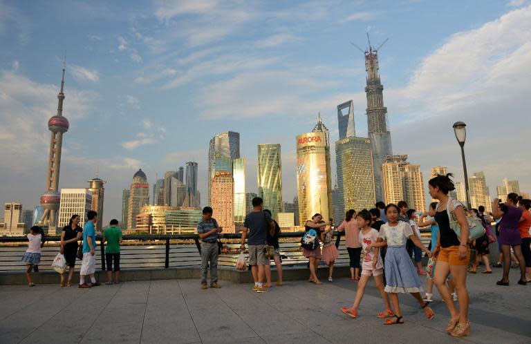 People look at the Shanghai skyline and the Shanghai Tower, with construction still in progress