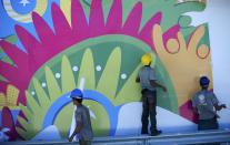 Workers erect a 2014 World Cup poster outside the Dunas arena soccer stadium in Natal, June 12 , 2014. Mexico will face Cameroon in their 2014 World Cup football match here on June 13. REUTERS/Dylan Martinez