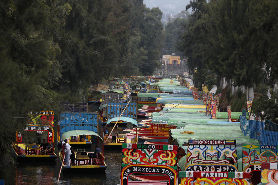 A few boats carrying passengers make their way past dozens of parked trajineras, the colorful boats typically rented by tourists, families, and groups of young people, in Xochimilco, Mexico City, Friday, Sept. 6, 2019. The usually festive Nativitas pier was subdued and largely empty Friday afternoon, with some boat operators and vendors estimating that business was down by 80% on the first weekend following the drowning death of a youth that was captured on cellphone video and seen widely in Mexico. Borough officials stood on the pier to inform visitors of new regulations that went into effect Friday limiting the consumption of alcohol, prohibiting the use of speakers and instructing visitors to remain seated.(AP Photo/Rebecca Blackwell)
