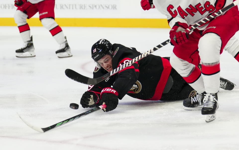 Ottawa Senators right wing Drake Batherson (19) reaches for the puck as he falls to the ice while taking on the Carolina Hurricanes during the second period of an NHL hockey match in Ottawa, Ontario, on Tuesday, Dec. 12, 2023. (Sean Kilpatrick/The Canadian Press via AP)