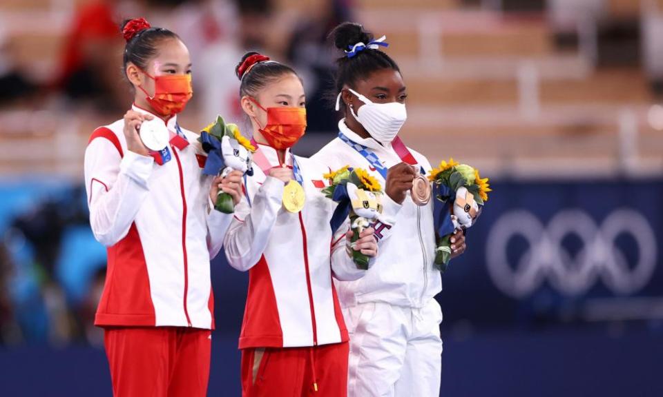 Gold medallist Guan Chenchen of China celebrates on the podium with silver medallist, Tang Xijing of China and bronze medallist, Simone Biles of the US.