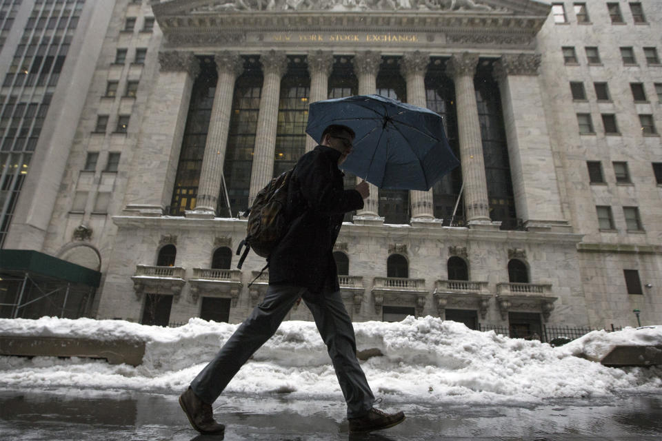 A man walks past the New York Stock Exchange in New York's financial district February 13, 2014.  A deadly winter storm moved north along the East Coast of the United States on Thursday, bringing heavy snow, sleet and rain across the Washington, D.C., and New York areas, grounding flights and shutting government offices.