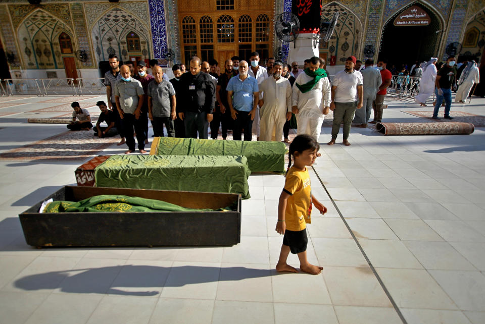 Mourners pray in a mosque before burying victims of a Monday bombing at a crowded Baghdad market busy with shoppers a day before the Muslim Eid al-Adha holiday, in Najaf, Iraq, Tuesday, July 20, 2021. ​Iraqi medical officials said the Monday bomb attack in Sadr City, a Baghdad suburb, killed at least 30 people and wounded dozens of others. (AP Photo/Anmar Khalil)