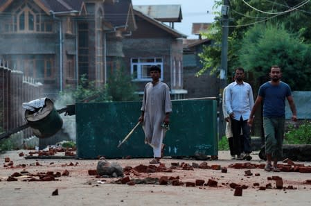 Kashmiris walk past a blockade put up by residents ahead of the Eid-al-Adha prayers during restrictions after the scrapping of the special constitutional status for Kashmir by the Indian government, in Srinagar