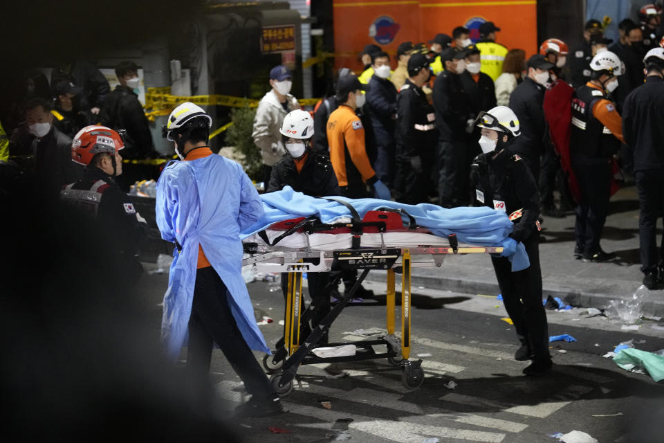 Rescue workers carry a victim on the street near the scene in Seoul, South Korea, Sunday, Oct. 30, 2022. Scores of people were killed and others were injured as they were crushed by a large crowd pushing forward on a narrow street during Halloween festivities in the capital, South Korean officials said. (AP Photo/Lee Jin-man)