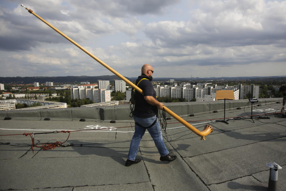 A musician with an alphorn walk on the rooftop of an residence building during the sound check for the 'Himmel ueber Prohils', Sky over Prohlis, concert event in Dresden, Germany, Saturday, Sept. 12, 2020. About 33 musicians of the Dresden Sinfoniker perform a concert on the rooftops of the Dresden neighbourhood Prohlis. (AP Photo/Markus Schreiber)