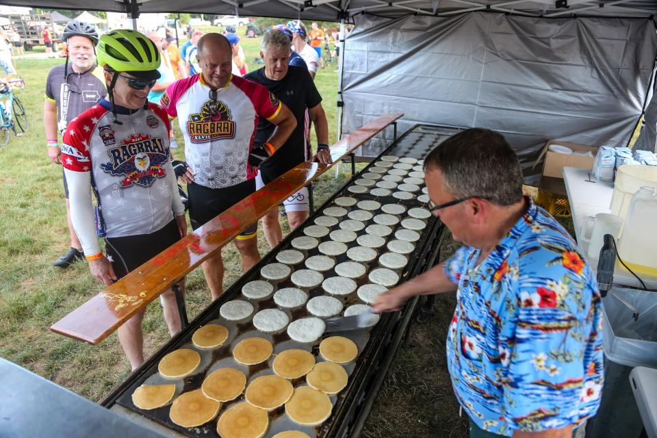 Darren White flips pancakes at Chris Cakes stand at a Bronson park on the first day of RAGBRAI 49 in 2022.