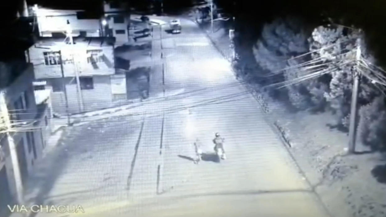 The moment a woman that appears to be holding a baby and a man on a motorcycle, walk away from the place where the body was later found, on the 9th April, in Soacha, Colombia.