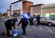 Baltimore police officers tackle and arrest looters after they emerged from a "Deals" store with merchandise during clashes between rioters and police in Baltimore, Maryland April 27, 2015. REUTERS/Jim Bourg