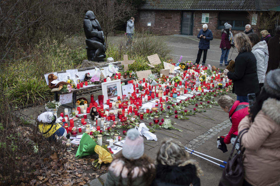 A women lights a candle at the main entrance of the Zoo in Krefeld, Germany, Thursday, Jan. 2, 2020. Three woman are under investigation for launching paper sky lanterns blamed for setting off a fire that destroyed an ape house at the zoo in the first few minutes of the new year, killing more than 30 animals, officials said Thursday. (Marcel Kusch/dpa via AP)