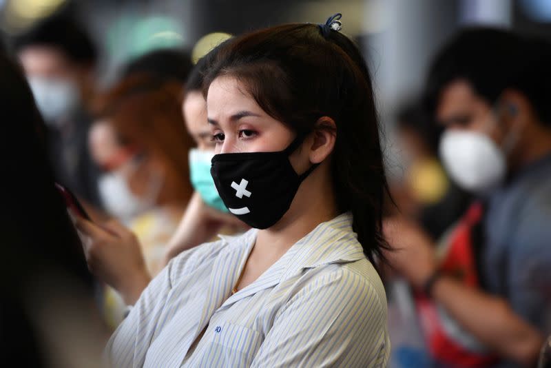 A commuter waits for a train wearing a protective mask at the Skytrain BTS in Bangkok