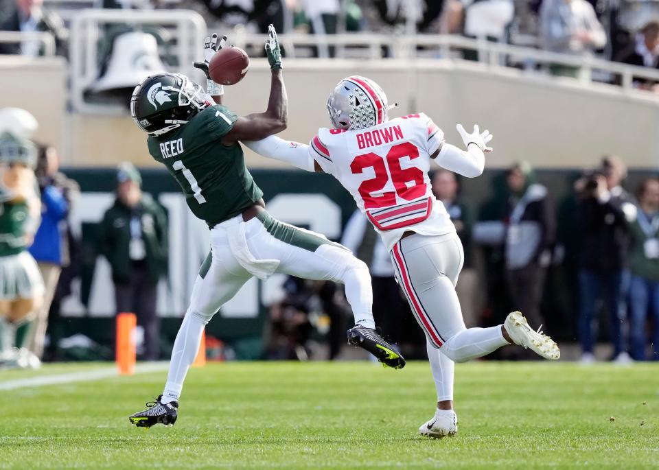 Oct 8, 2022; East Lansing, Michigan, USA; Michigan State Spartans wide receiver Jayden Reed (1) makes a catch against Ohio State Buckeyes cornerback Cameron Brown (26) in the first quarter of the NCAA Division I football game between the Ohio State Buckeyes and Michigan State Spartans at Spartan Stadium. 