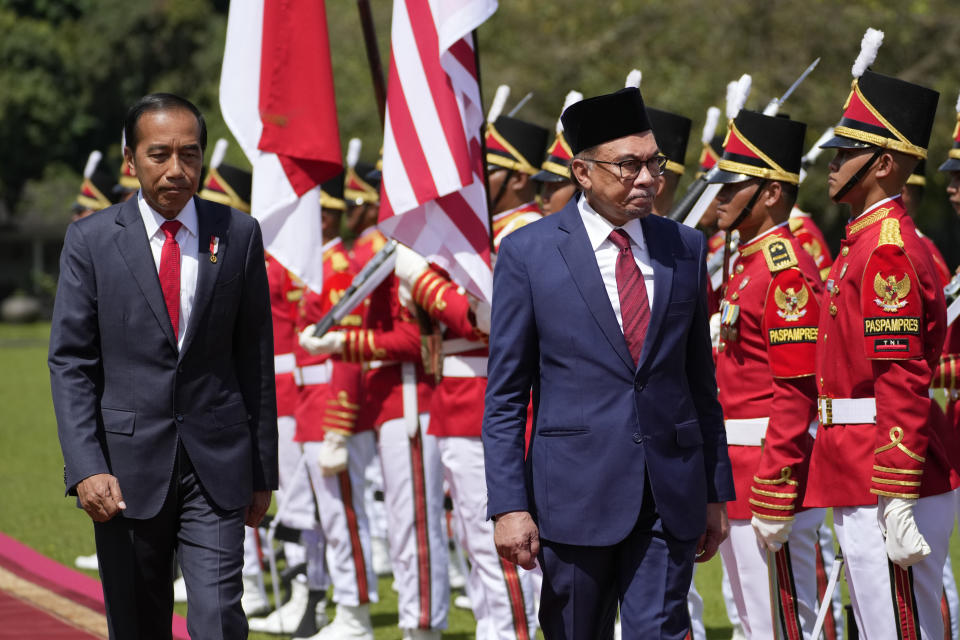 Malaysian Prime Minister Anwar Ibrahim, right, inspects honor guards with Indonesian President Joko Widodo during their meeting at the presidential palace in Bogor, West Java, Indonesia, Monday, Jan. 9, 2023. (AP Photo/Achmad Ibrahim)