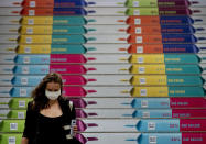 A woman with face mask walks down stairs with chocolate advertising in the main train station after arriving in Frankfurt, Germany, Wednesday, Sept. 16, 2020. (AP Photo/Michael Probst)