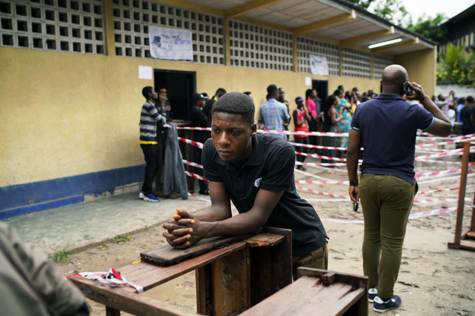 Congolese voters wait at the St. Raphael school in the Limete district of Kinshasa Sunday, Dec. 30, 2018, for voter's listings that have not arrived. People had started to gather at 6am to cast their votes, and four hours later, vote had not started as the lists were not available. Forty million voters are registered for a presidential race plagued by years of delay and persistent rumors of lack of preparation. (AP Photo/Jerome Delay)