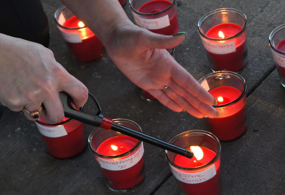 Jessica Henry lights candles during a small March 2021 ceremony to honor Bruce Herba and others who have lost their lives to the coronavirus. A wreath and lit candles with the names of others were placed during the gathering at James A. Nance Park in Indialantic.