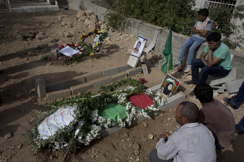 FILE - In this Sept. 7, 2015 file photo, Palestinians mourn at the graves of Riham Dawabsheh, 27, her husband Saed Dawabsheh and their 18-month-old son Ali, in the West Bank village of Duma, near Nablus. On Monday, Sept. 14, 2020, the Lod District Court handed down three life sentences to Jewish extremist Amiram Ben-Uliel convicted in a 2015 arson attack that killed the Palestinian toddler and his parents. (AP Photo/Nasser Nasser, File)