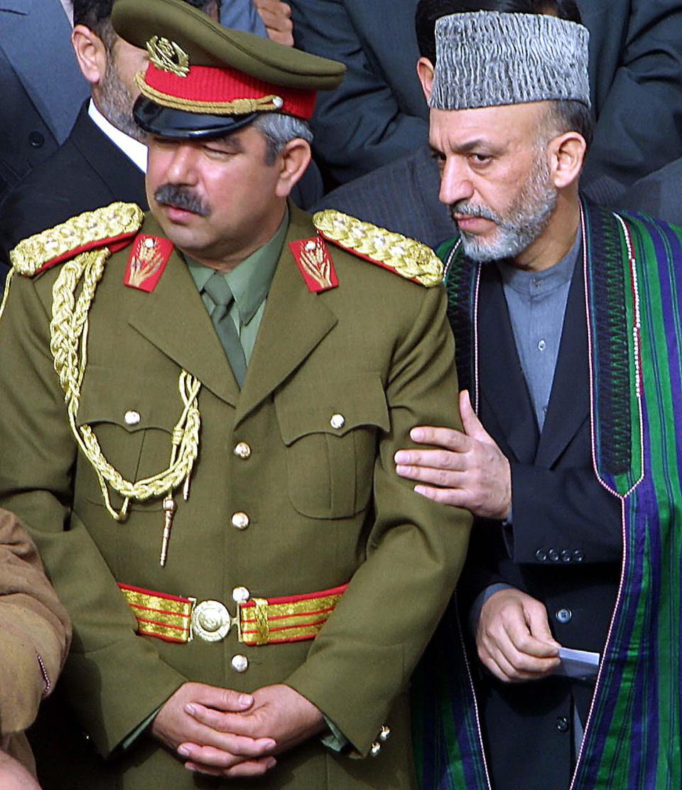 Afghan interim government leader Hamid Karzai (R) touches the arm of powerful warlord and Afghan deputy defence minister, General Abdul Rashid Dostum, during a ceremony held at Rosa Sharif Azrat Ali shrine, 21 March 2002, in Mazar-i-Sharif to mark the traditional Afghan new year.  Thousands of people came out to attend ceremonies at the shrine under tight security, the first such celebrations since the former Taliban regime banned such ceremonies over five years ago.    AFP PHOTO/HOANG DINH NAM (Photo credit should read HOANG DINH NAM/AFP via Getty Images)