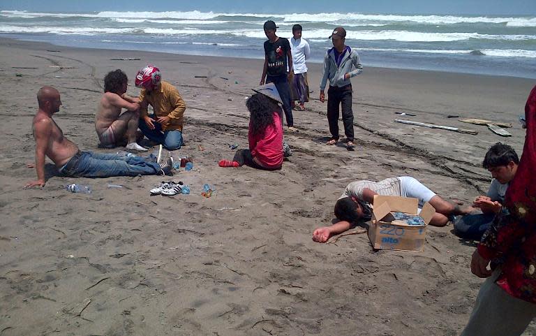 Residents help a group of asylum-seeker survivors on the beach after being rescued by locals in the coastal village of Cianjur, located in Indonesia's western Java island on September 27, 2013