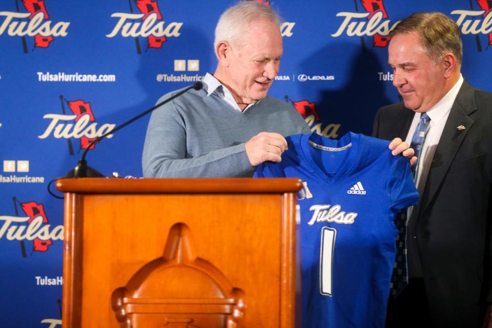 Tulsa athletic director Rick Dickson presents new head football coach Kevin Wilson a football jersey during an NCAA college football press conference at the University of Tulsa on Tuesday, Dec. 6, 2022, in Tulsa, Okla.