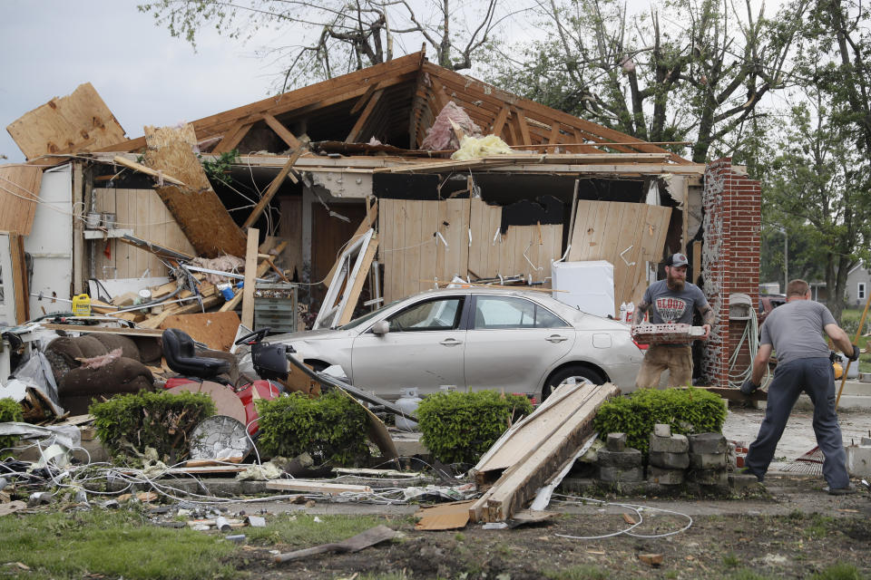 Residents and volunteers clean debris from damaged homes that litters the properties on Fairground Road after a tornado storm system passed through the area the previous night, Tuesday, May 28, 2019, in Celina, Ohio. A rapid-fire line of apparent tornadoes tore across Indiana and Ohio overnight, packed so closely together that one crossed the path carved by another. At least half a dozen communities from eastern Indiana through central Ohio suffered damage, according to the National Weather Service. (AP Photo/John Minchillo)