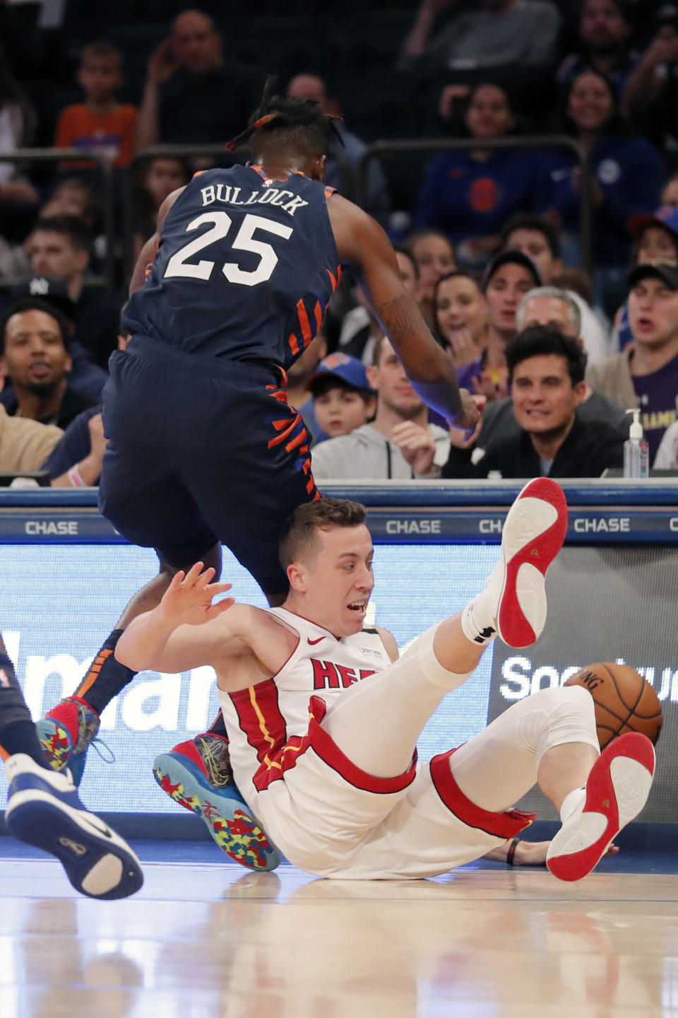 Miami Heat's Duncan Robinson, bottom, and New York Knicks' Reggie Bullock (25) dive after a loose ball during the second half of the NBA basketball game, Sunday, Jan. 12, 2020, in New York. The Knicks defeated the Heat 124-121. (AP Photo/Seth Wenig)